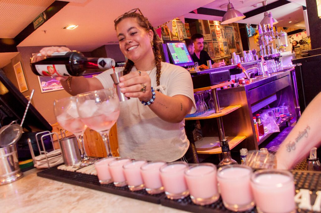 A bartender pours pink shots in Belushi's Barcelona.