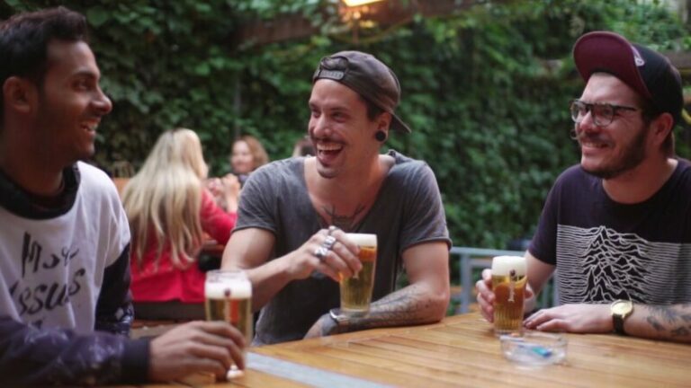 Three friends laughing on the terrace of a bar in Amsterdam.