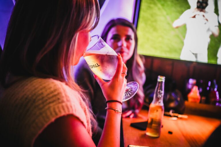 Two female friends watching football at a Belushi's Bar.