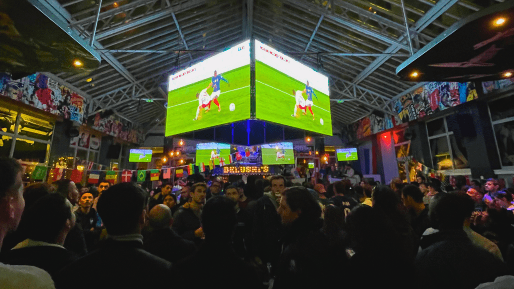 A huge cube screen in a Belushi's bar showing the World Cup.