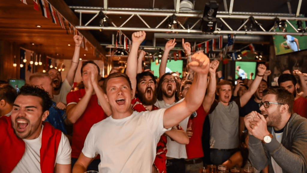 A group of football fans celebrate a goal in a Belushi's bar.