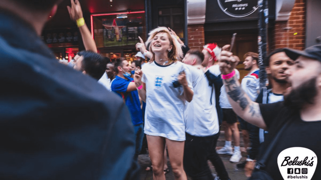 A female football fan celebrates a win outside a Belushi's Bar.