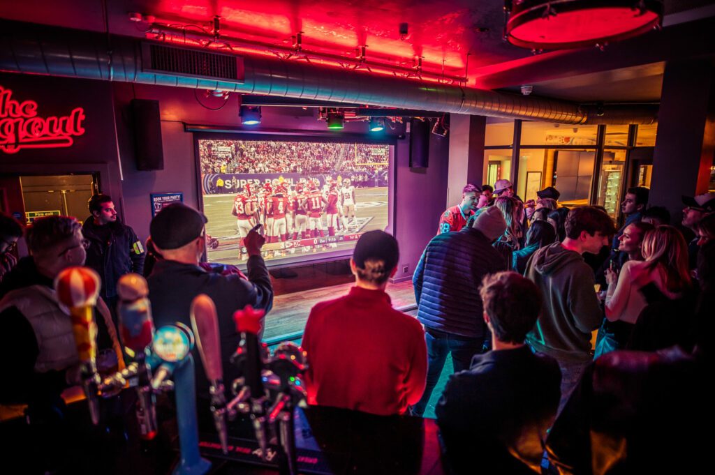 Fans watch the NFL on a big screen at a Belushi's Bar.