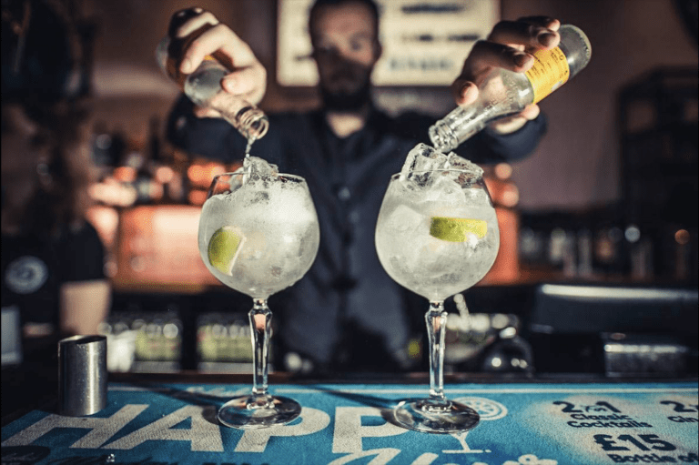 A barman pouring two gin and tonics