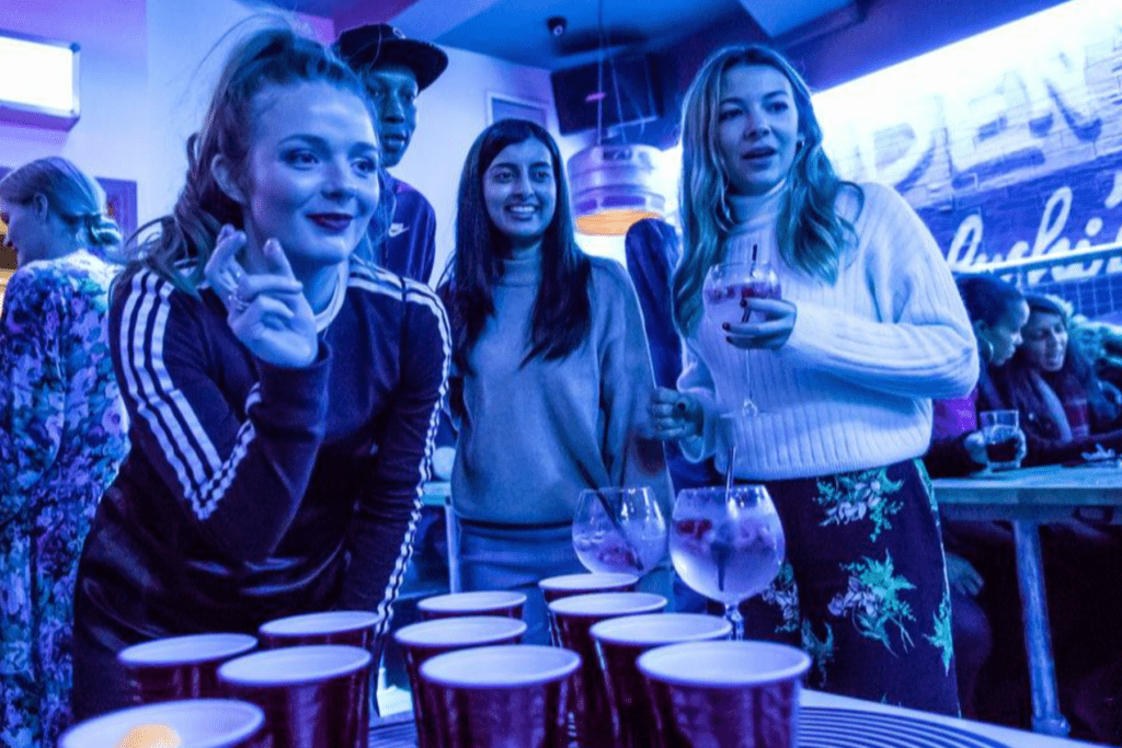 A group of friends play beer pong in a Belushi's Bar.