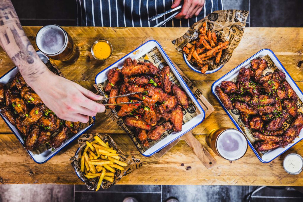 A chef uses a pair of tongs to serve up a platter of wings in a Belushi's Bar.