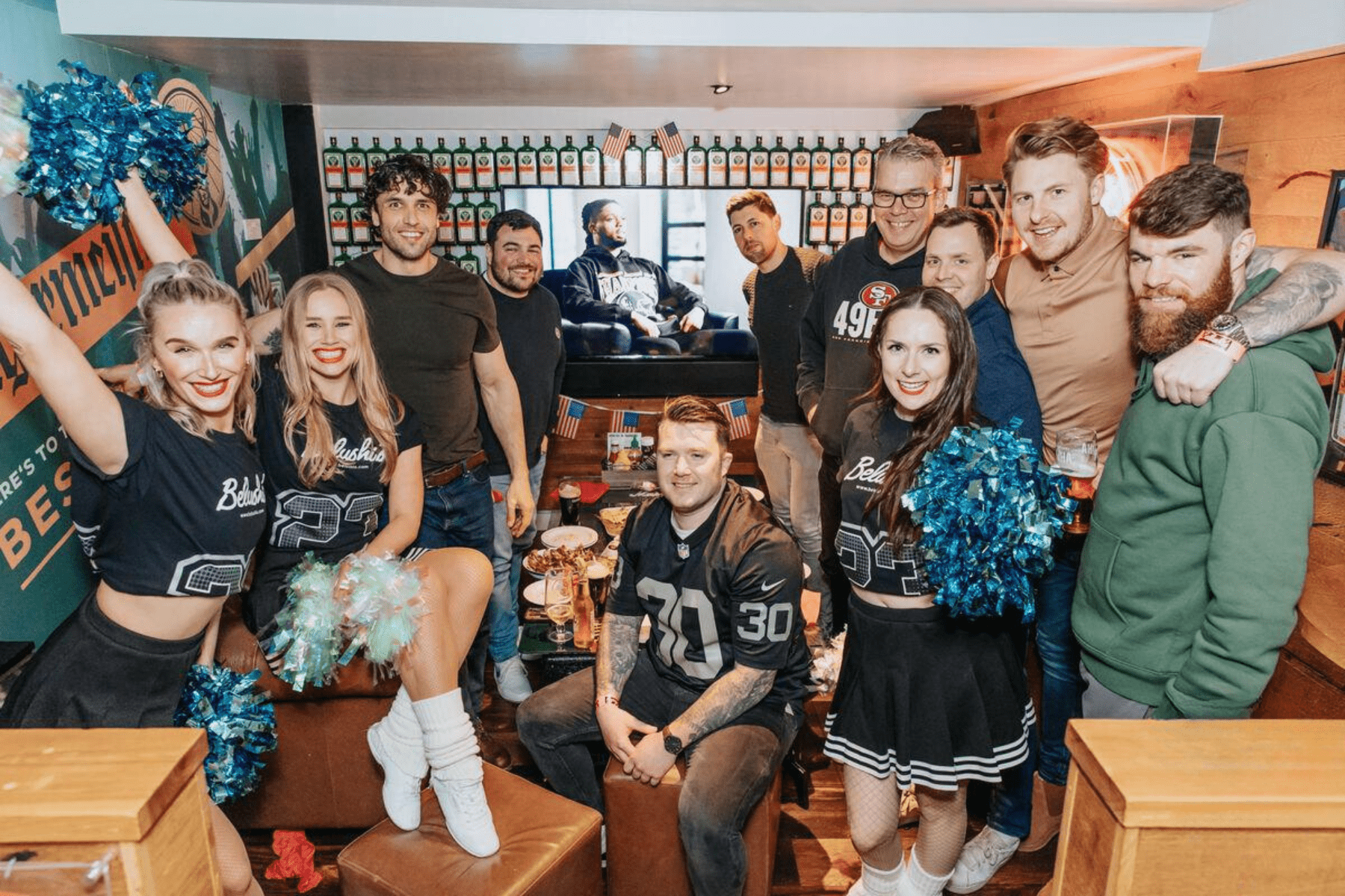 A group of friends with cheerleaders in a private space in Belushi's Bar.