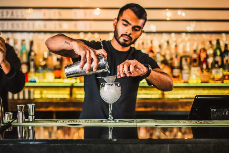 A bartender pours a cocktail in a large glass at Belushi's Bar.