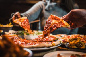 Friends pull cheesy pizza slices on a table at a Belushi's Bar.