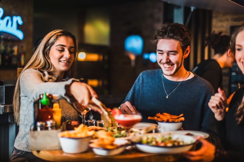 Friends laugh as they eat and drink at a Belushi's Bar.