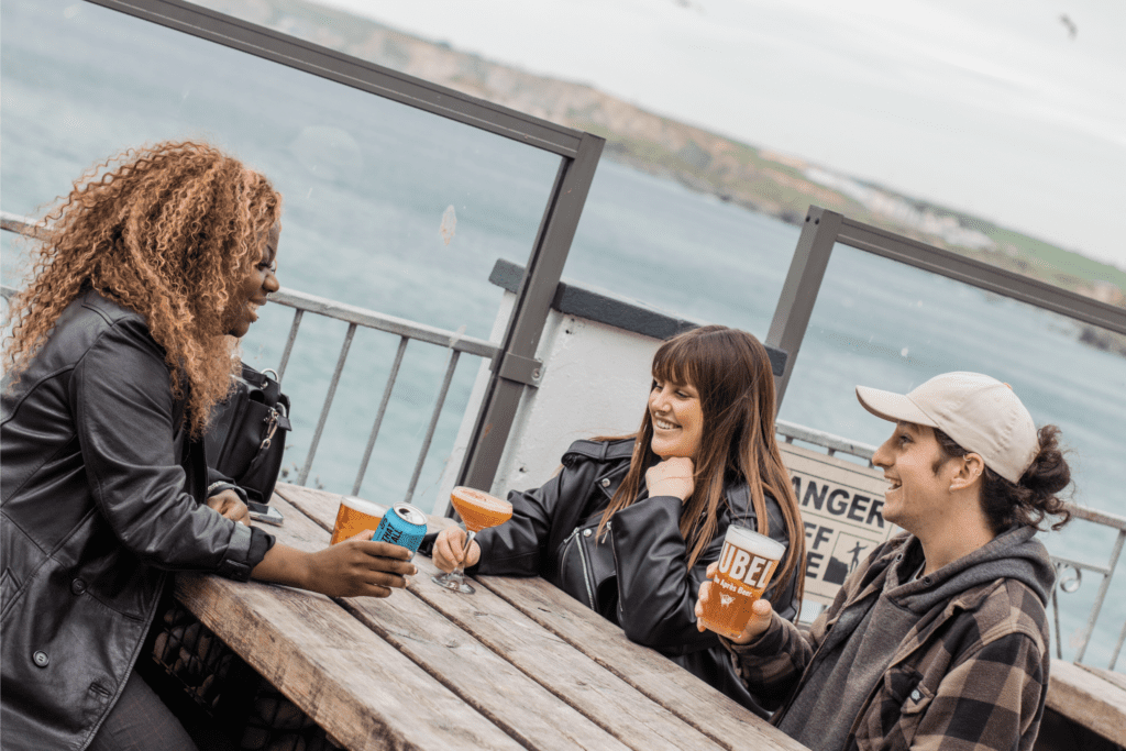 Friends drinking at laughing in an outside private hire space in Newquay.