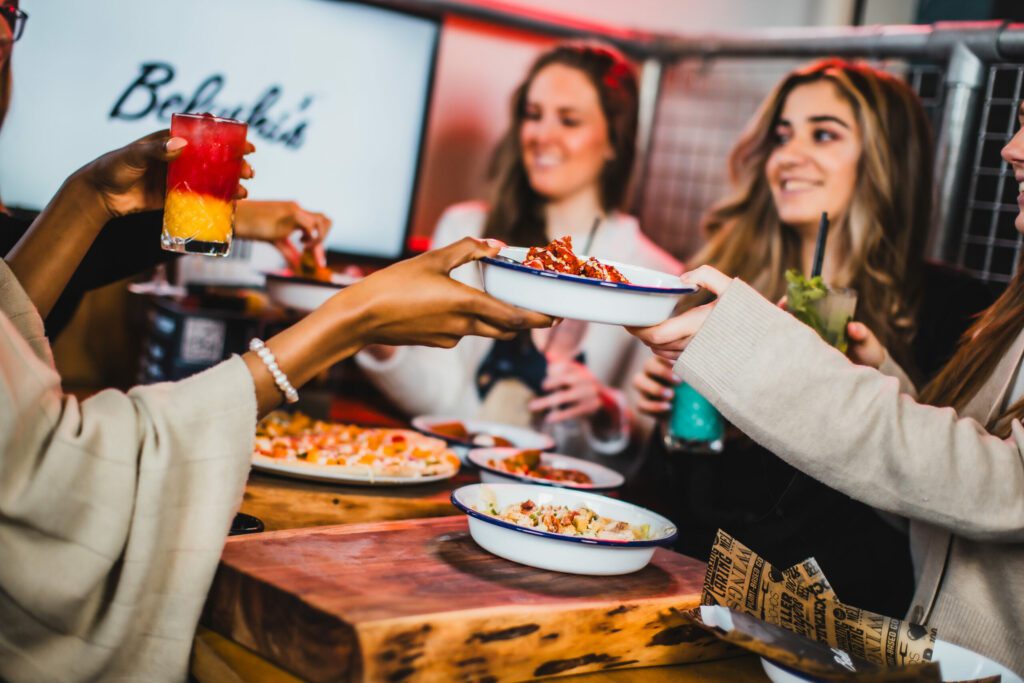 Friends passing food around in a booth at Belushi's Bar in Hammersmith.