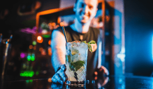 A cocktail being served by smiling bartender