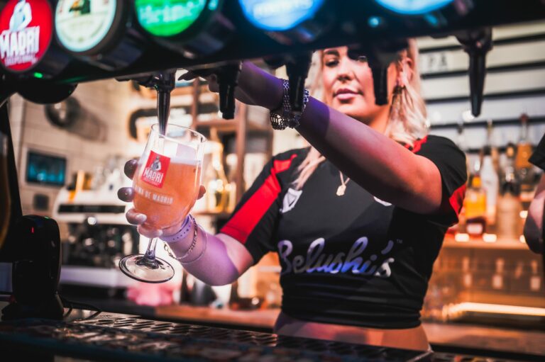 A female bartender pours a pint at a Belushi's Bar.