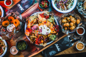 A picture of various sharing food available at Belushi's such as nachos, tater tots, doughnuts, and more.