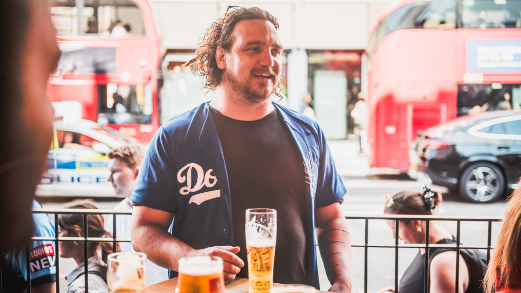 A customer enjoying a pint at a Belushi's London Bridge branch with double decker buses in the background.