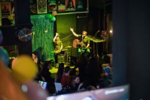 An image of two live musicians performing at a Belushi's bar, with customers both standing and seated watching the show