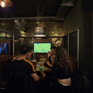 A group of customers sat in a booth watching football at a Belushi's bar