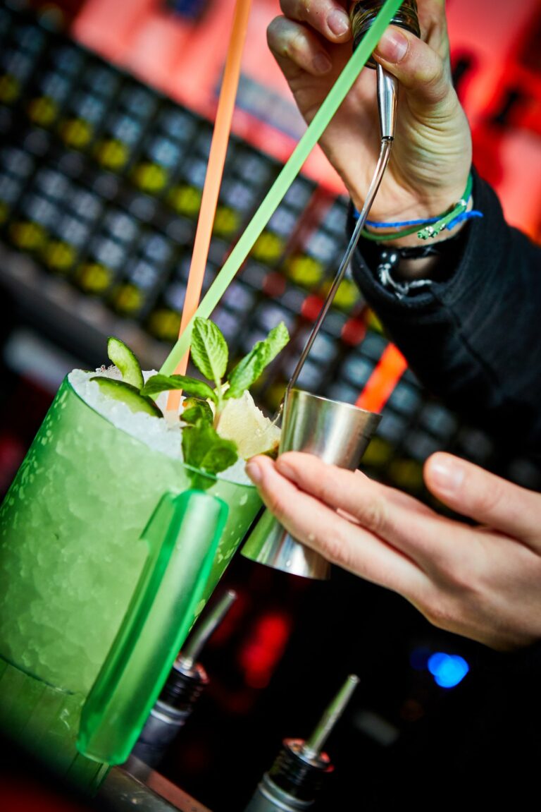 A Belushi's bartender making a colourful green cocktail