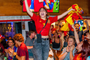 An image of a woman celebrating a Spanish football victory on top of a table at a Belushi's bar