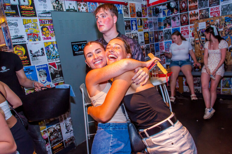 An image of two women hugging at a Belushi's bar