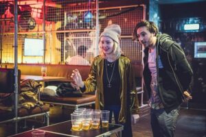 Two customers play beerpong at a Belushi's bar