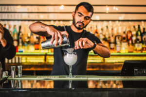 An image of a bartender pouring a cocktail into a balloon glass