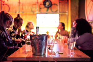 A picture of a group of friends. On the table there is a bucket of prosecco, served in glasses