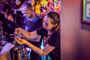 A picture of Belushi's bartenders making drinks behind the bar.