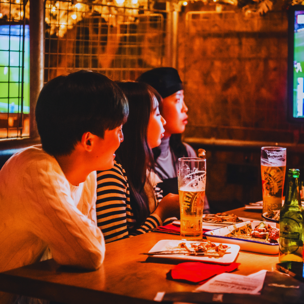 A group of friends watching football at a Belushi's bar while enjoying beers and food.