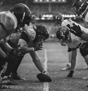 NFL players facing off with a football in the middle of the image.