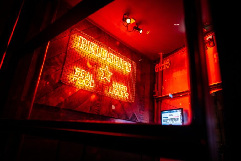 A picture of a booth at Belushi's with a neon sign that says 