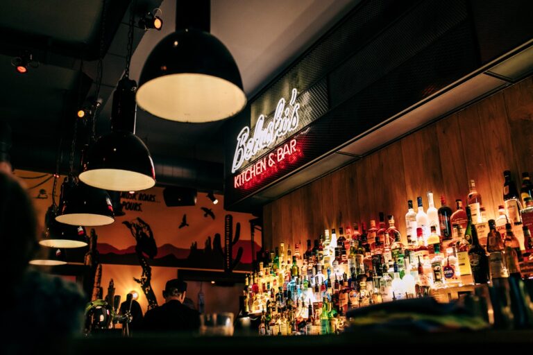 A picture of the backbar of a Belushi's bar, with a neon sign that says 