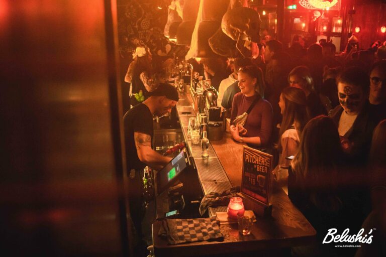 An image of a Belushi's bar decorated for Halloween, with customers waiting at the bar to be served